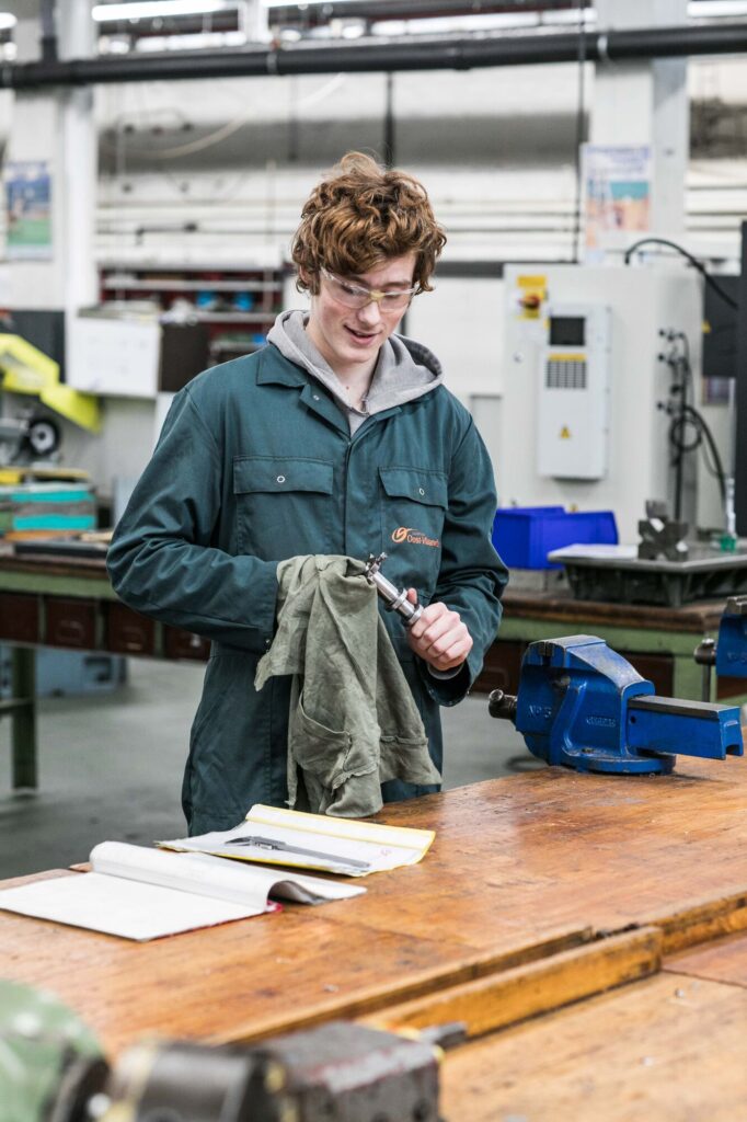 leerling met veiligheidsbril veegt werkmateriaal proper