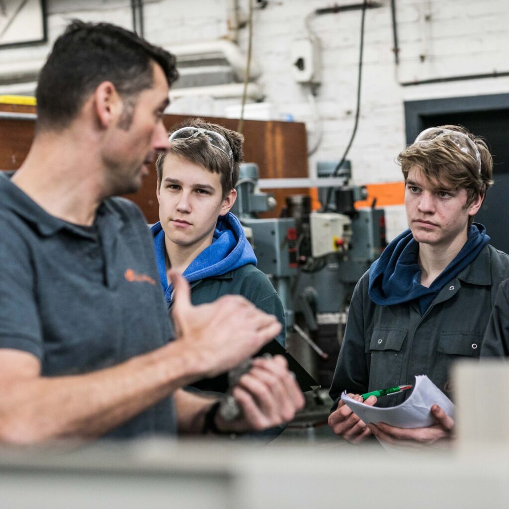 drie leerlingen krijgen uitleg van hun leerkracht in het atelier