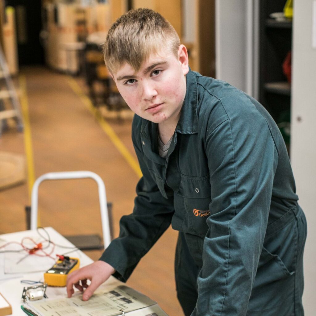 leerling bladert in een werkmap tijdens de praktijkles