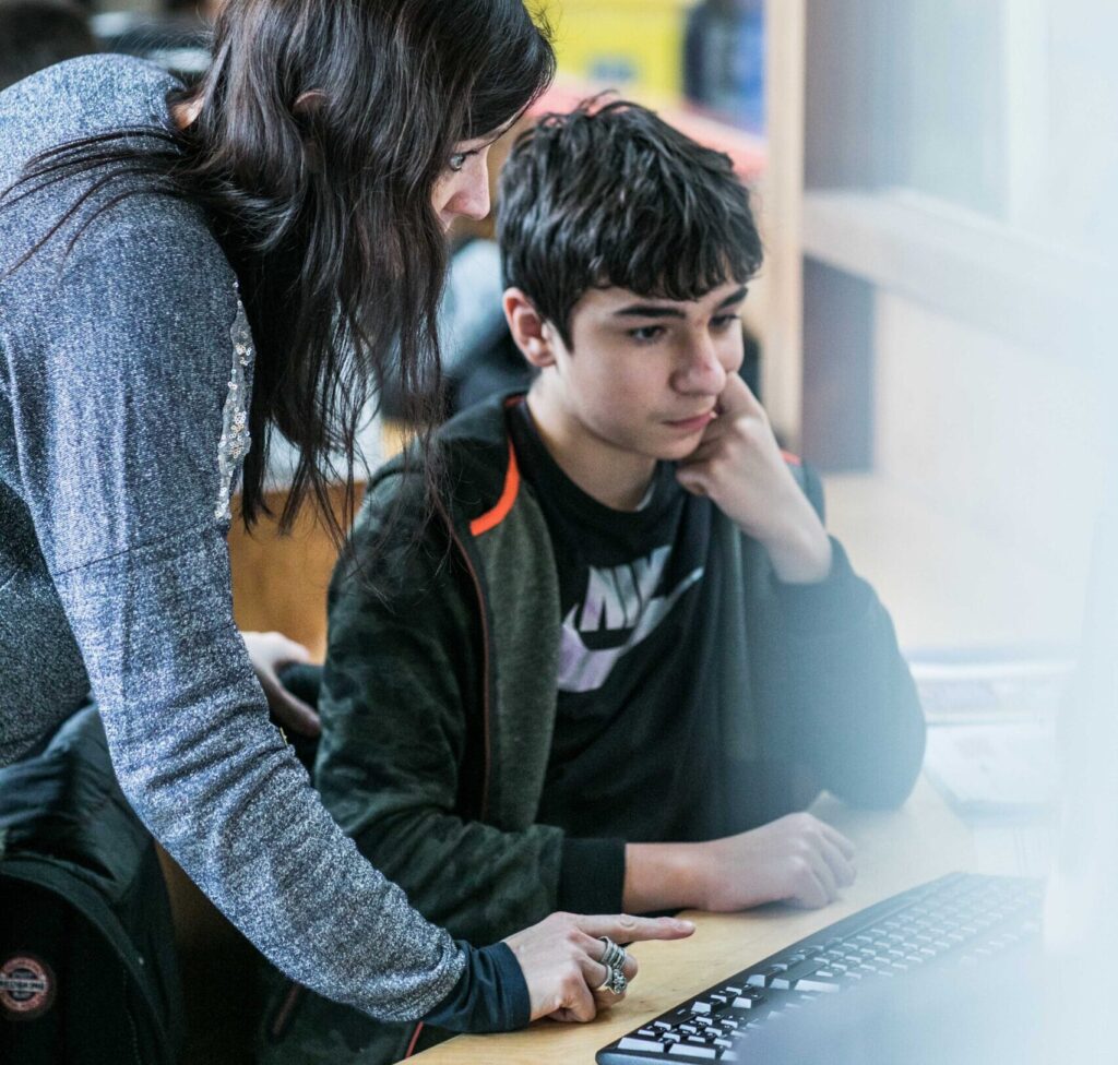 Leerkracht helpt leerling met taken op de computer