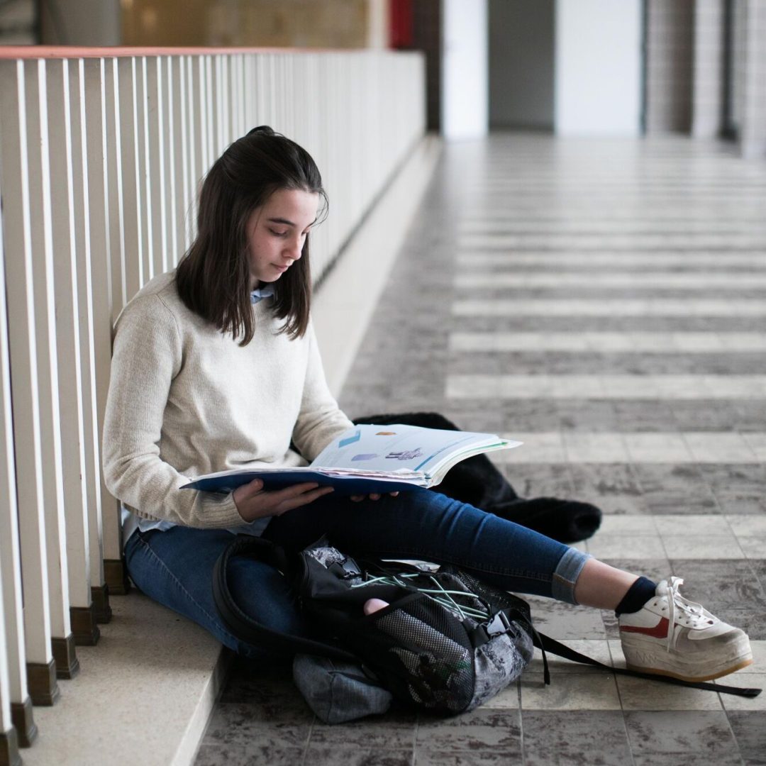 leerling zit in de gang en leest een boek