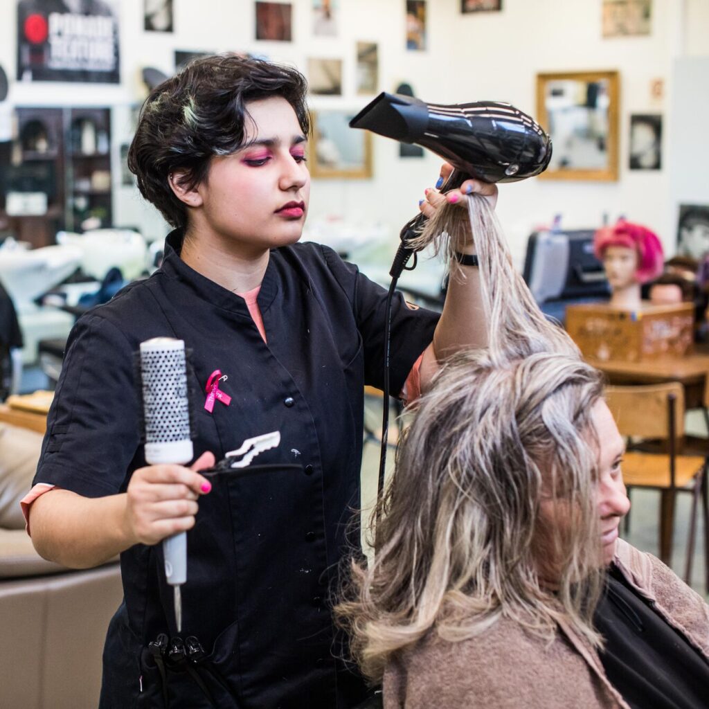 leerling brusht het haar van een klant