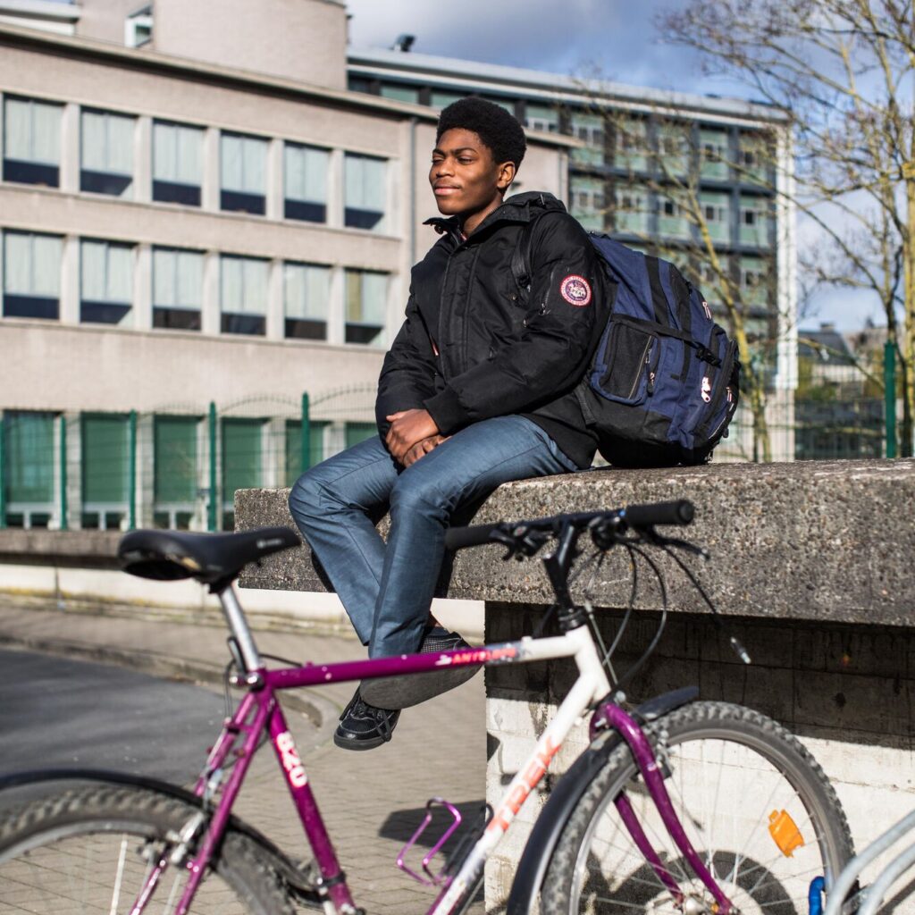 jongen zit op de speelplaats met een fiets naast zich