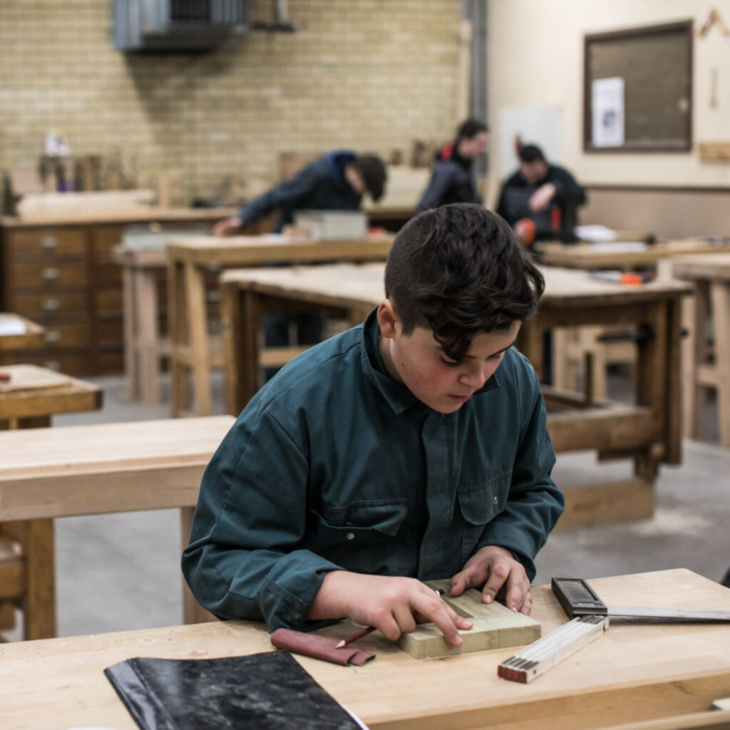 leerling hout aan het werk met een plank op een werkbank