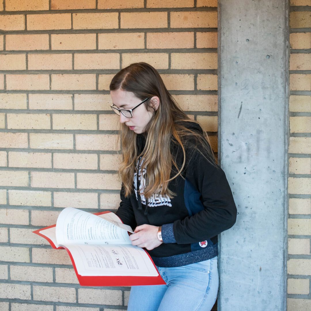 leerling leest een boek in de gang